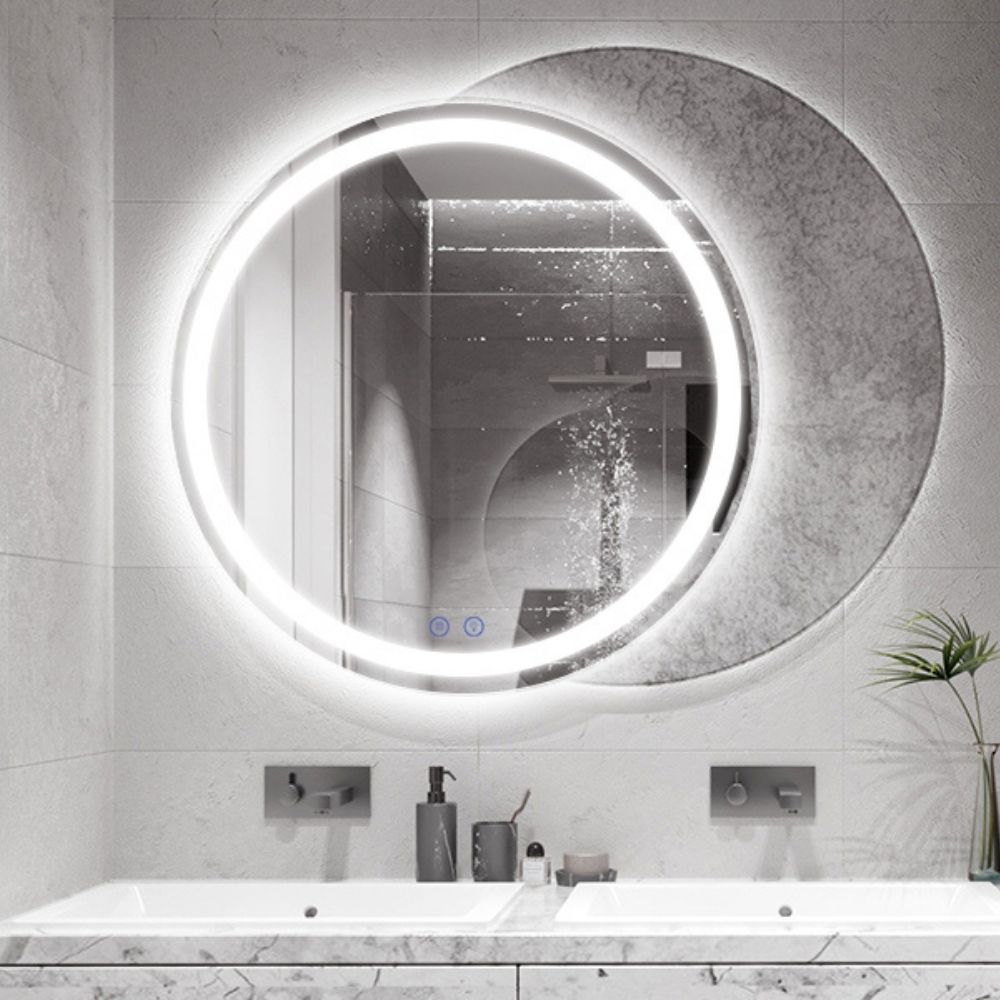A round frameless backlit LED bathroom mirror above a basin